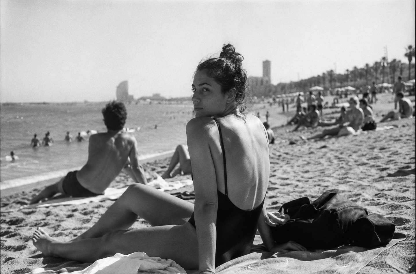 A woman on a Barcelona beach looks back over her shoulder toward the camera.
